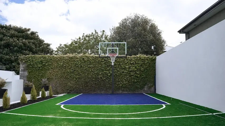 Outdoor basketball court next to pool house.
